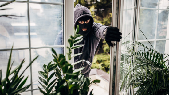 Burglar breaking into a house through the window